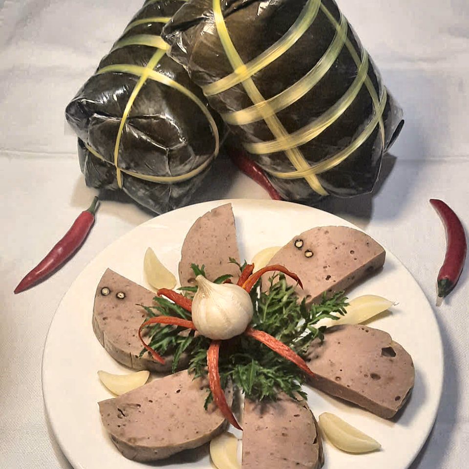 Chả bò Đà Nẵng cắt lát bày đĩa, bên cạnh cây chả gói lá